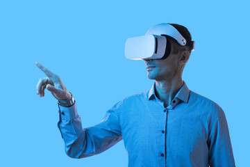 A professional male interacts with digital content using a virtual reality headset against a blue...