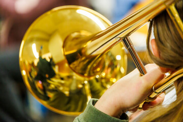 Obraz premium Trombone player with a golden brass instrument, close-up view with reflections on the bell