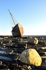 A fishing boat stranded on a rocky shore.