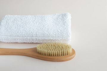 dry massage brush and white cotton towel on light plain background