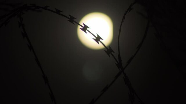 Moon rising behind prison fences and metal wires