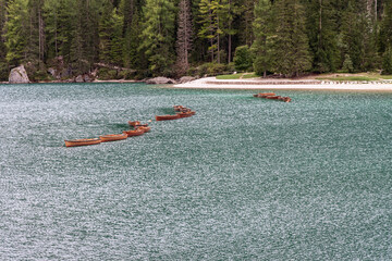 Wooden boats floating on the rippled turquoise waters of Lake Braies near a sandy shoreline...