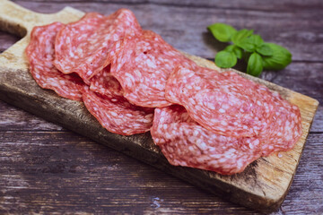 Slices Of  Traditional Italian  dried thinly sliced   artisan  pork salami Milano .Antipasti  salami on a wooden  cutting board