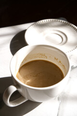 Hot coffee cup and coasters with blur black background. Vertical a cup of coffee in morning vibe. Hot drink, latte, shadow, breakfast, drink at home, natural light concepts for beverage image.
