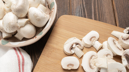 Fresh champignon mushrooms. Cutting champignon on cutting board.