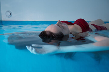 A young woman is swimming relaxed in a small pool.