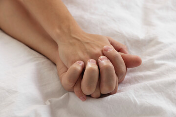 Lovely couple holding hands in bed, closeup