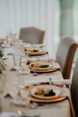 A beautifully set wedding reception table featuring elegant beige chairs, meticulously plated...