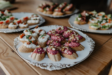 An elegant display of gourmet appetizers featuring assorted bruschetta with creamy cheese, beetroot spread, sun-dried tomatoes, walnuts, and fresh herbs, beautifully arranged on decorative vintage 