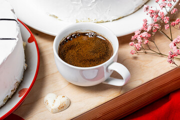 Americano espresso coffee in a white cup with a saucer, two strong coffees, red background, romantic breakfast, coffee with foam, red flowers in the background, roses, gypsophila, cake