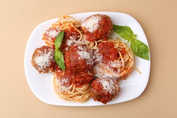 Delicious pasta with meatballs, basil and cheese on beige table, top view