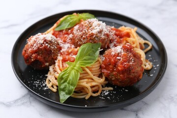 Delicious pasta with meatballs, basil and cheese on white marble table, closeup