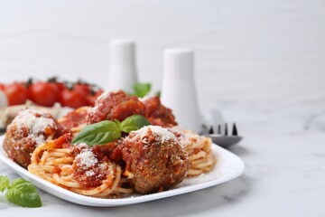 Delicious pasta with meatballs, basil and cheese on white table, closeup. Space for text