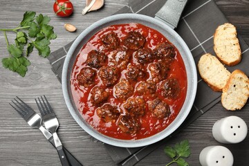 Delicious meatballs with tomato sauce served on wooden table, flat lay