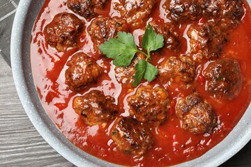 Delicious meatballs with tomato sauce in frying pan on wooden table, top view