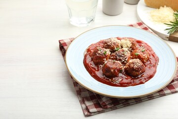 Delicious meatballs with tomato sauce, parmesan and herbs in on white wooden table. Space for text