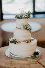 A beautifully designed three-tier rustic wedding cake with a semi-naked buttercream finish, adorned...