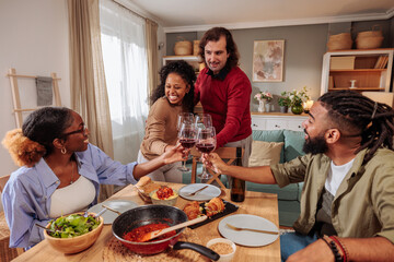 Friends raising a toast at dinner table at home