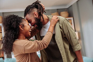 Couple laughing and hugging while dancing at home