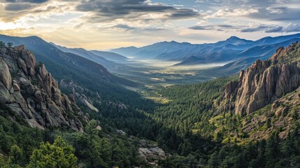 Obraz premium Panoramic view of a serene mountain valley at sunrise, showcasing lush green forests, rocky cliffs, and a misty valley floor.