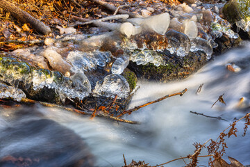 whitewater stream in winter, long exposure, water mist forms ice sculptures on the bank with phascinating light effects