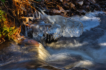 whitewater stream in winter, long exposure, water mist forms ice sculptures on the bank with phascinating light effects