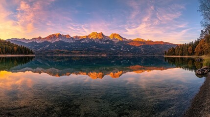 Panoramic view of a calm lake reflecting a mountain range at sunset.