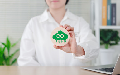 Reduce CO2 emission concept. Woman holding green CO2 emissions symbol, representing carbon footprint awareness, net zero, and carbon neutrality. Climate change, Global warming, Greenhouse gas,