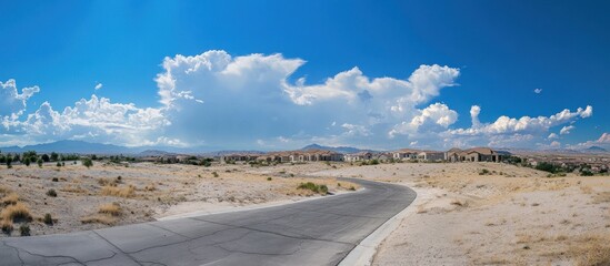 Winding road in a desert landscape with houses and blue sky.