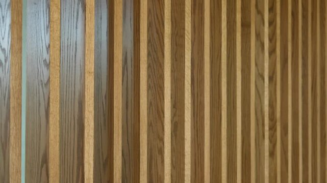 Series of vertical wooden slats or panels arranged in parallel, creating pattern of alternating light and dark wood grains. Texture and pattern created by wood