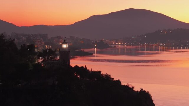 A cinematic footage of the lighthouse in Chalkida as it flashes during sunrise, with an orange-colored sky