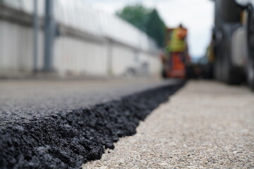 Close-Up Detail of Fresh New Asphalt Layer Edge, Showing Thickness and Even Distribution on Road Surface