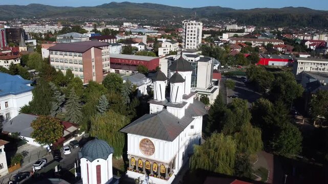 Drone landscape view of church Toti Sfintii surrounded by the urban city of Valcea on a sunny day