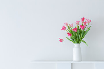 pink tulips in white vase on white background