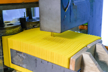Modern factory for working with foam rubber. At initial stage of production, orange cube passes...