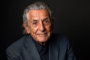 Obraz premium Senior man with silver hair and warm smile poses against a dark background showcasing wisdom and character in a classic portrait