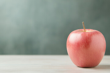 fresh red apple sits on wooden table against soft green background