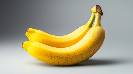 Two ripe bananas with visible textures and shadows on neutral background
