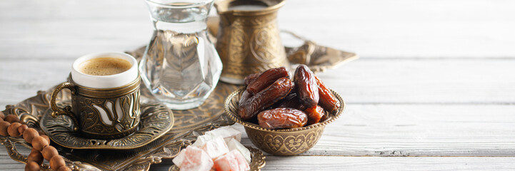 Cup of coffee and glass of water and dry dates on saucer ready to eat for iftar time. Islamic religion and ramadan concept.