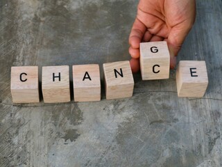 CHANGE and CHANCE concept. hand hold one letter on wooden blocks changes the word change to chance,...
