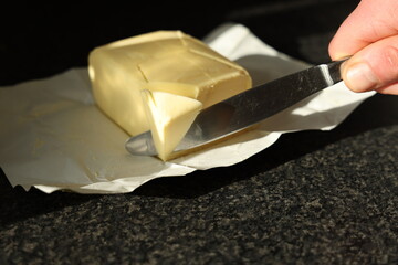 hand cutting a piece of butter
