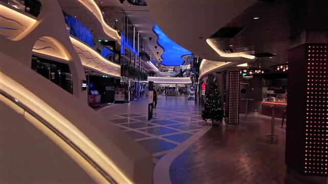 A stylish onboard view of MSC World Europa, featuring futuristic architecture, illuminated walkways, and elegant design. The ship&rsquo;s shopping and dining area is decorated for the holiday season.
