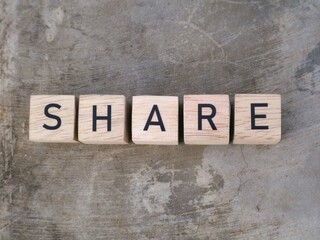 Naklejka premium Top view of SHARE word on wooden cube letter block on textured gray background. Motivation concept for organization or social community