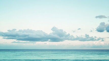 Obraz premium Serene ocean view with pastel sky and soft clouds formations over horizon
