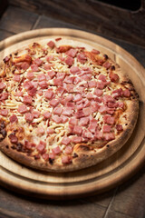 Pizza with ham and mozzarella cheese on wooden background. Soft focus. Close up	