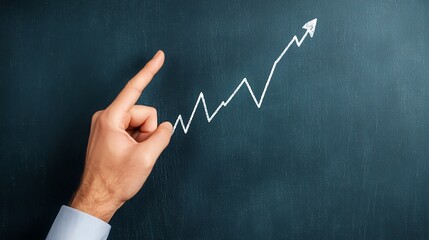 A hand points upward at a graph with an ascending line on a chalkboard, symbolizing progress and growth.