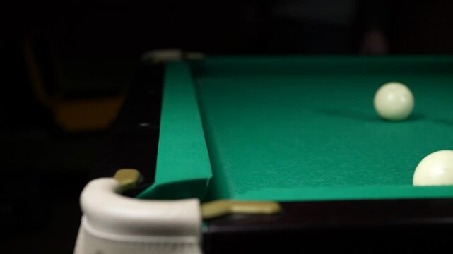 Young man playing American billiard pool poule close-up. Colorful balls on green billiards table .Billiard balls with numbers on a pool table. Billiards team sport.