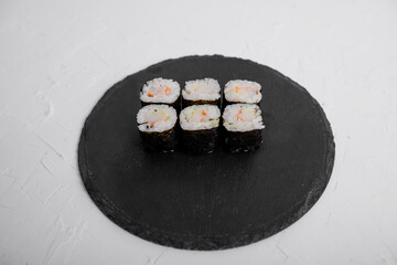 Close-up of six shrimp maki sushi rolls wrapped in nori, served on a black slate plate. Fresh and traditional Japanese cuisine with rice and seafood.