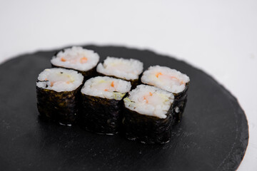 Close-up of six shrimp maki sushi rolls wrapped in nori, served on a black slate plate. Fresh and traditional Japanese cuisine with rice and seafood. © farmuty