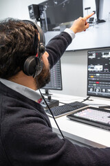 A television director in a broadcast control room, actively guiding a live production. Surrounded...